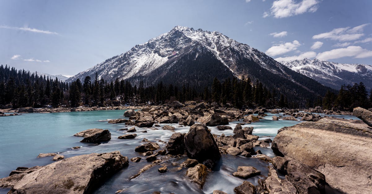Stunning mountain landscape with flowing river and forest backdrop.